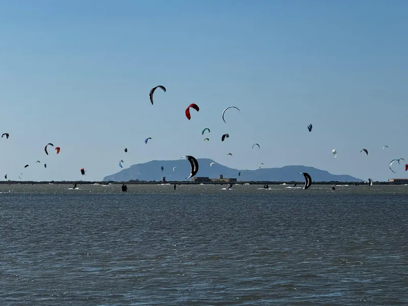 Decine di kite colorati sulla laguna dello Stagnone, con un'isola sullo sfondo